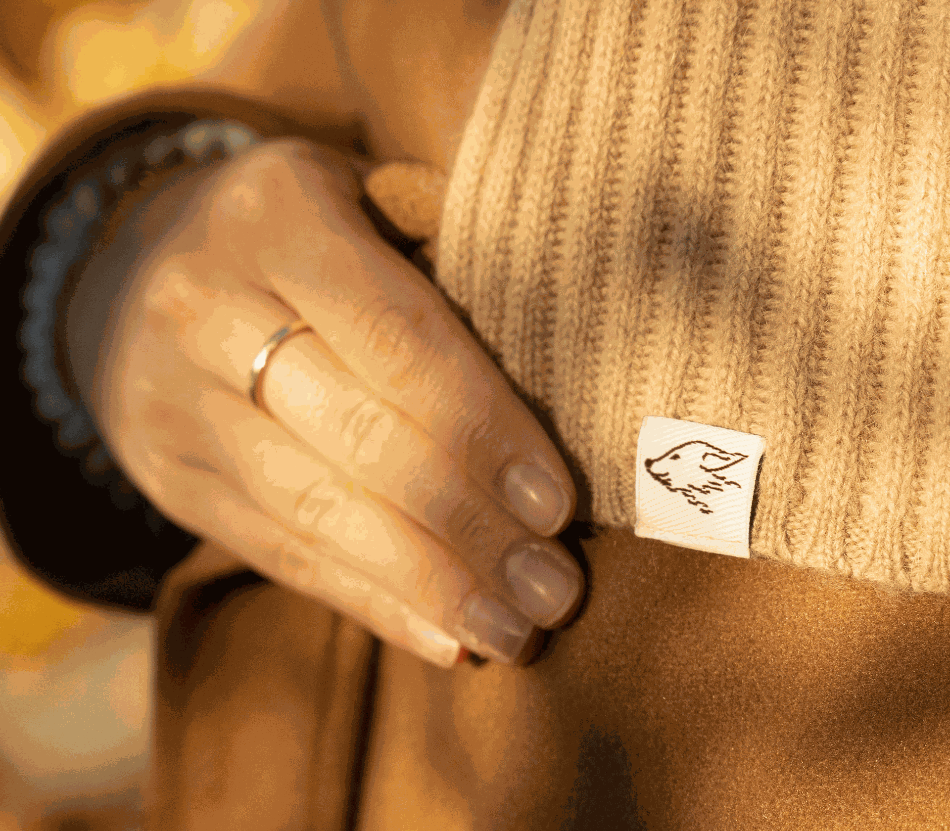 Detailbild des beigen Schals aus Kamelbild, der mit einer braunen Jacke kombiniert wurde.