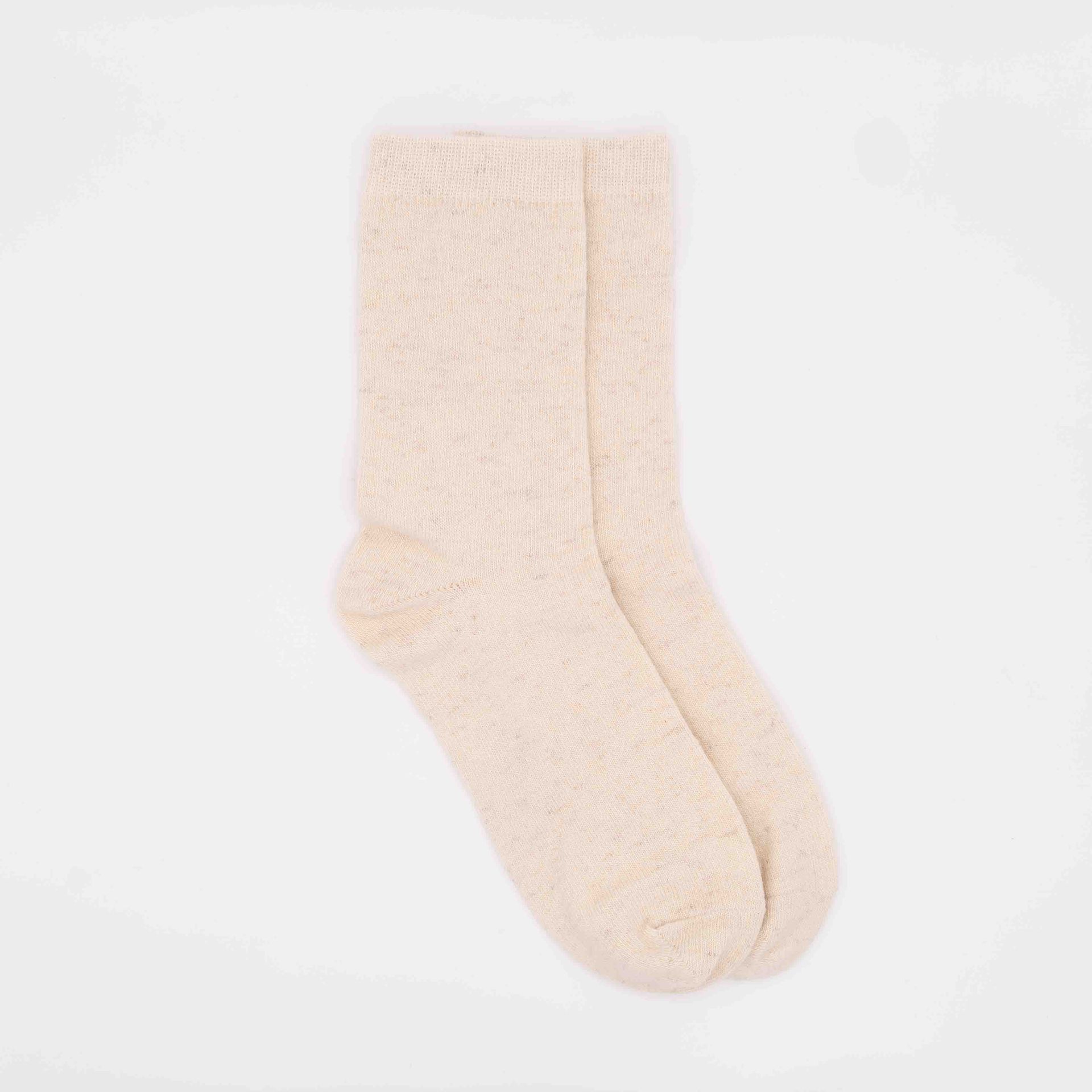Weiße Socken aus Wolle liegen flach vor grauem Untergrund