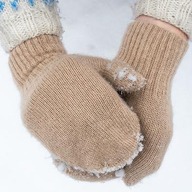 Beige Handschuhe formen eine Schneekugel