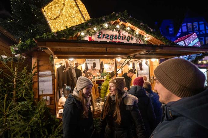 Ein Weihnachtsmarktstand mit einem leuchtenden Paket und vielen Leuten davor