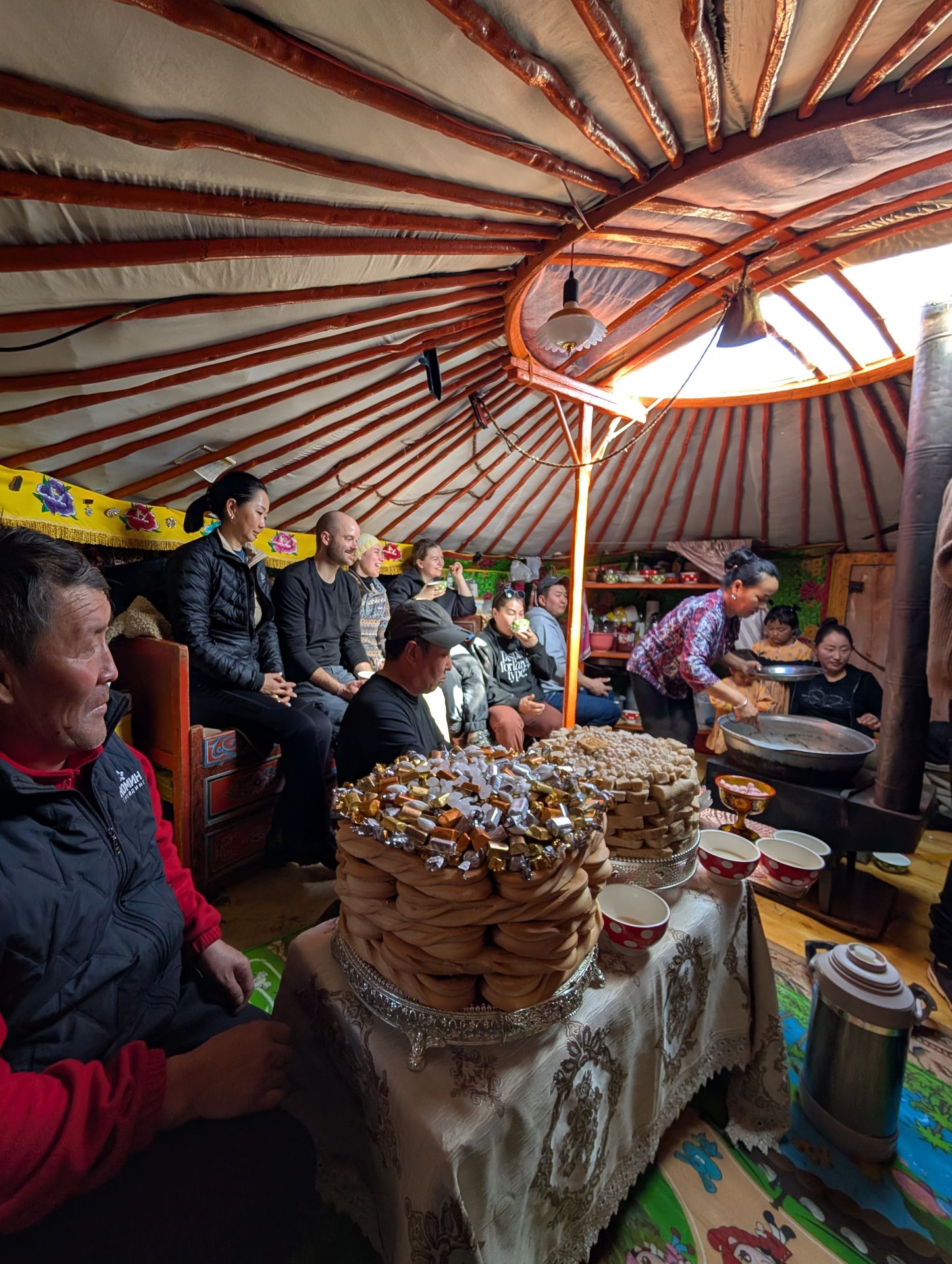 Foto aus einer Jurte in der viele Menschen vor Essen sitzen