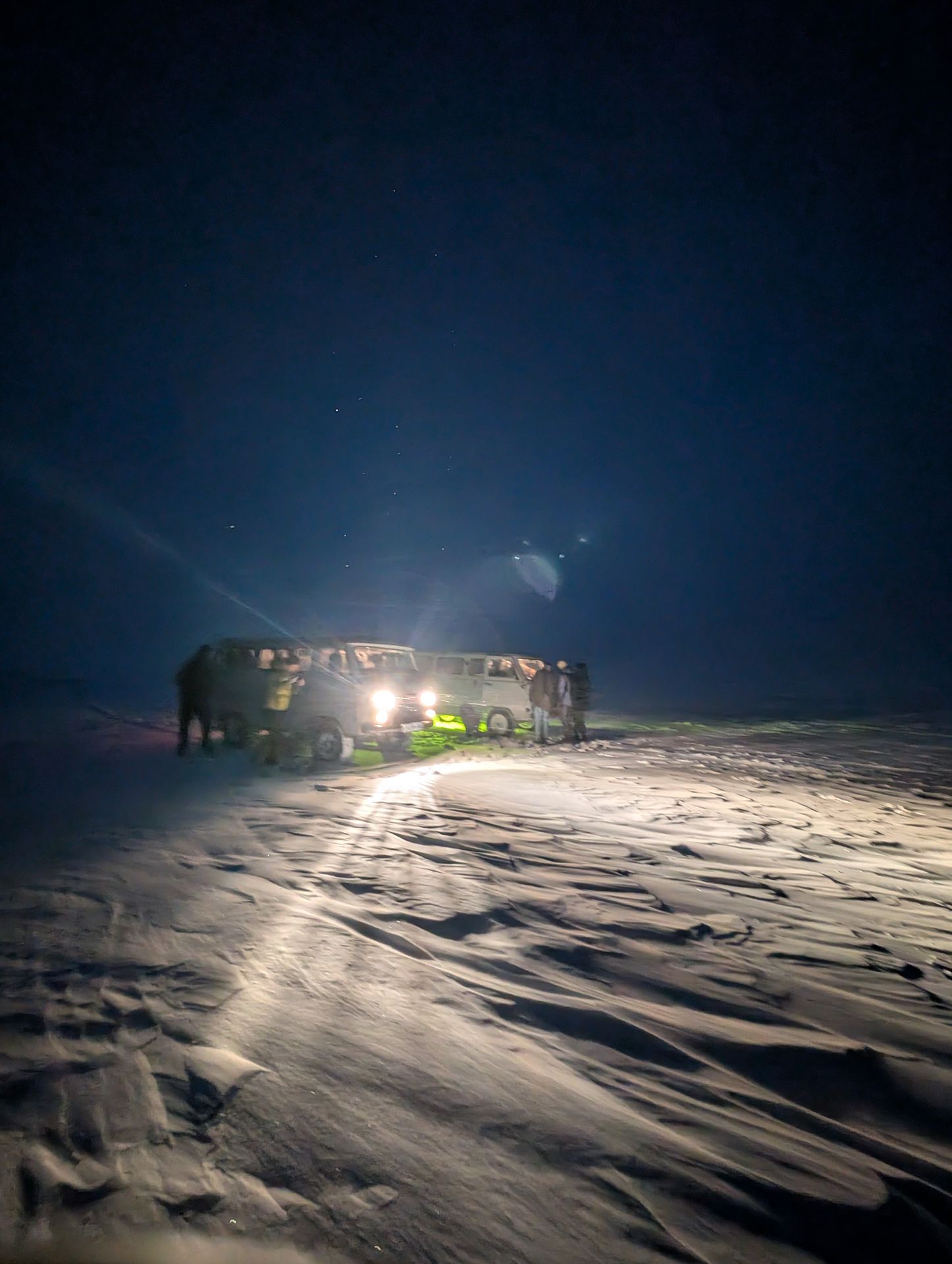 Zwei Autos stehen auf Schneeverwehungen im Dunkeln