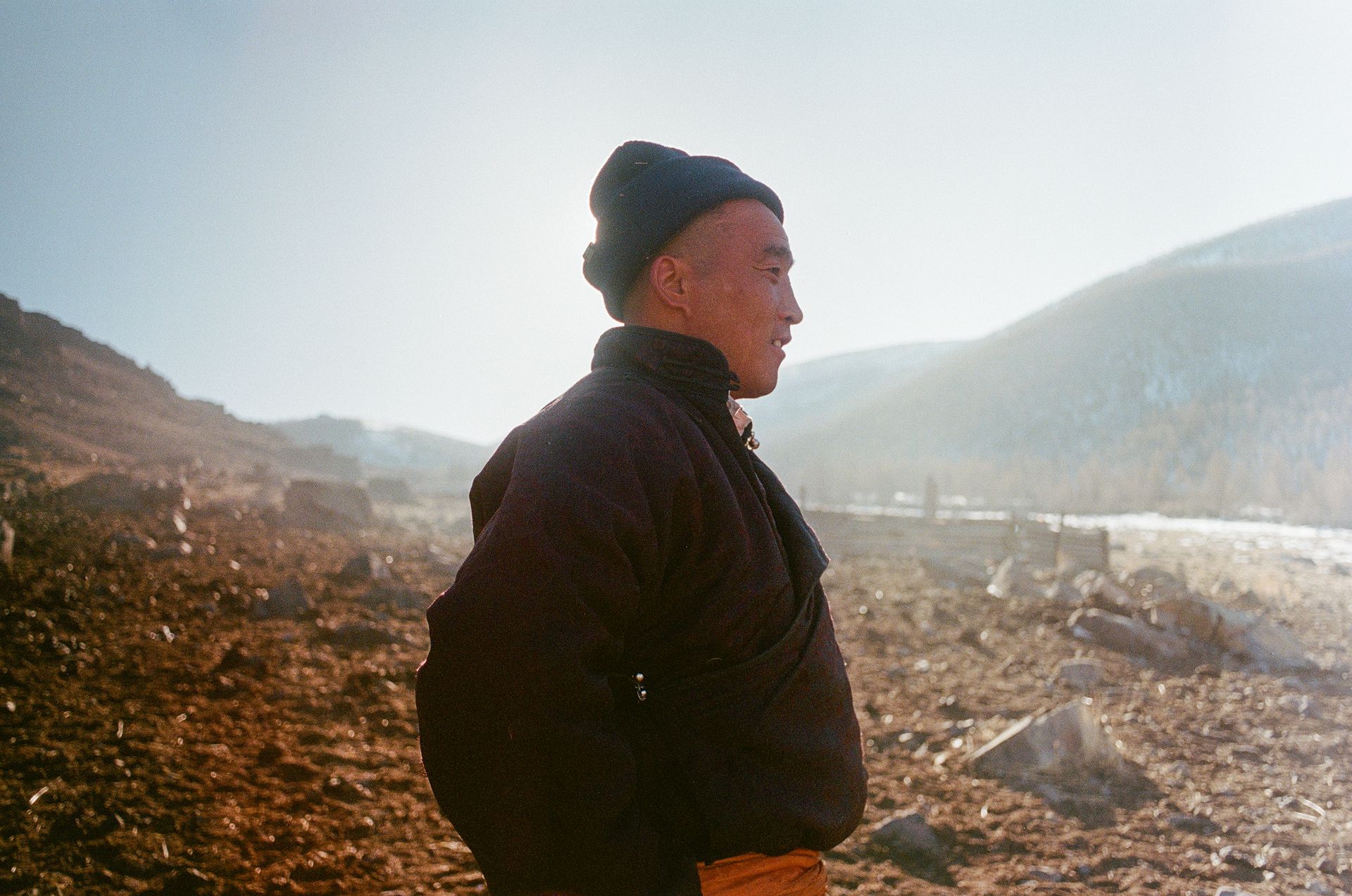 Ein mongolischer Mann blickt in die Landschaft – Wintersonne über den Bergen.