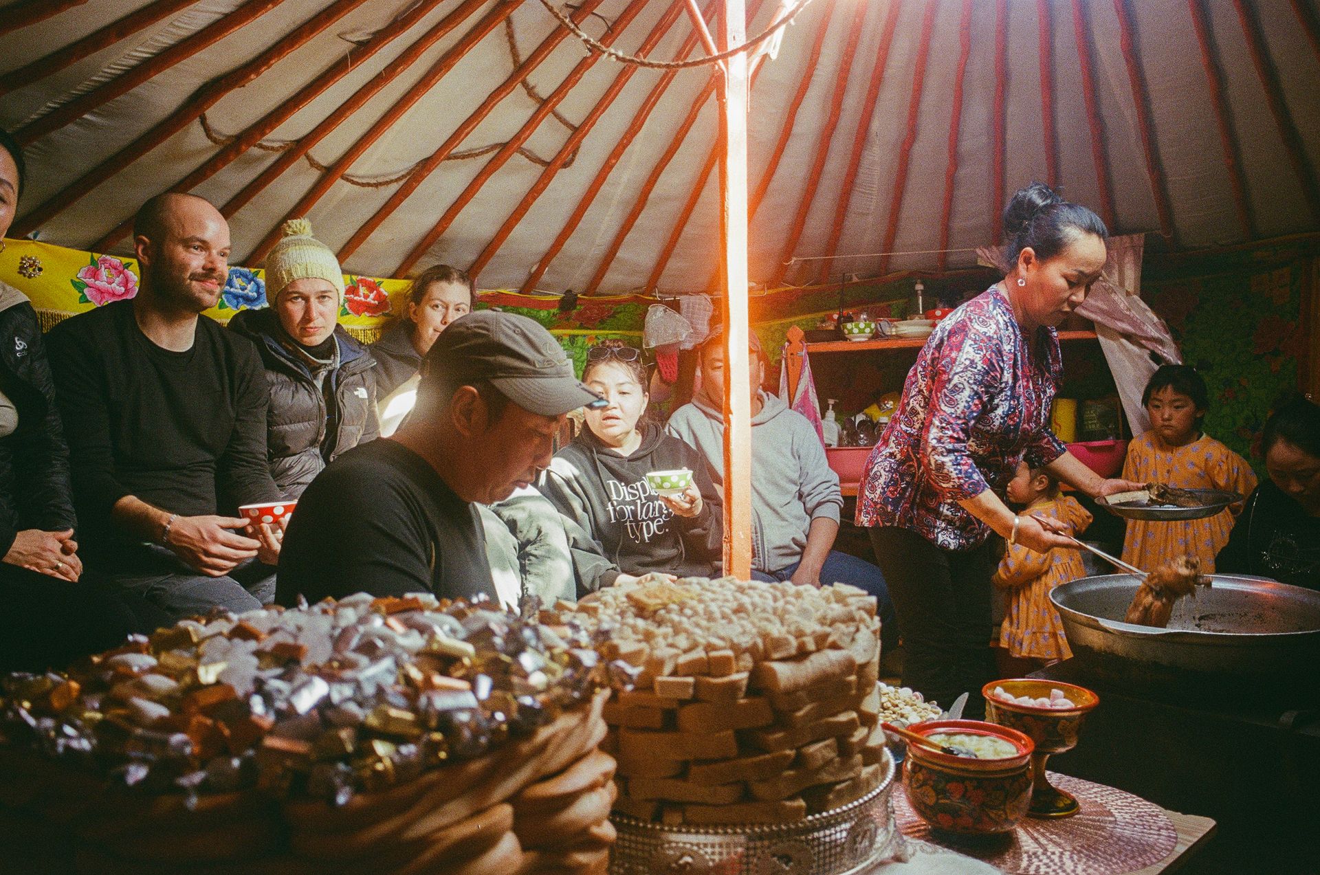 Innenaufnahme einer Jurte mit mongolischer Familie beim gemeinsamen Essen und Teezubereiten.