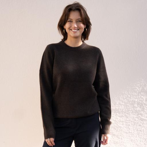 Frau in dunklem Pullover vor beiger Wand