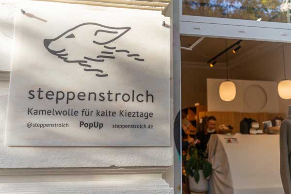 Close-up of a wooden sign with a gray paw print logo and German text describing the product on a sales stand.