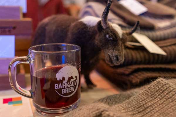 A glass of Bahkauv Brew stands next to a felted yak.