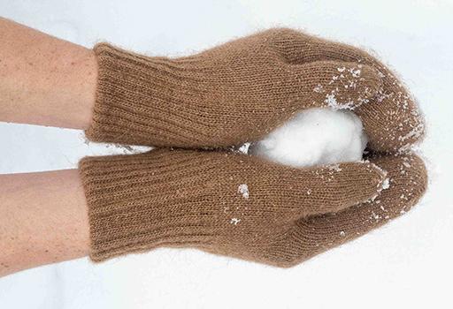 Braune Handschuhe aus Wolle halten einen Schneeball
