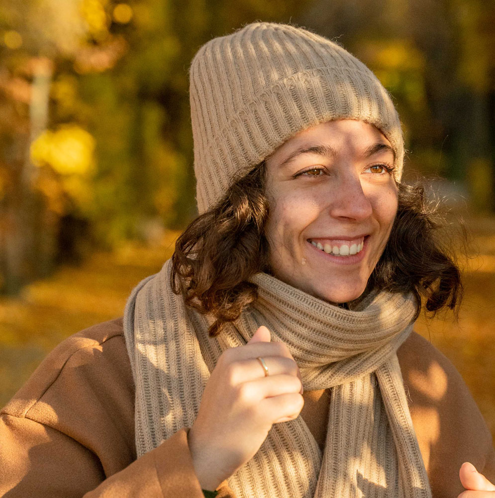 Lachende Frau mit beiger Mütze aus Wolle und Schal aus Wolle