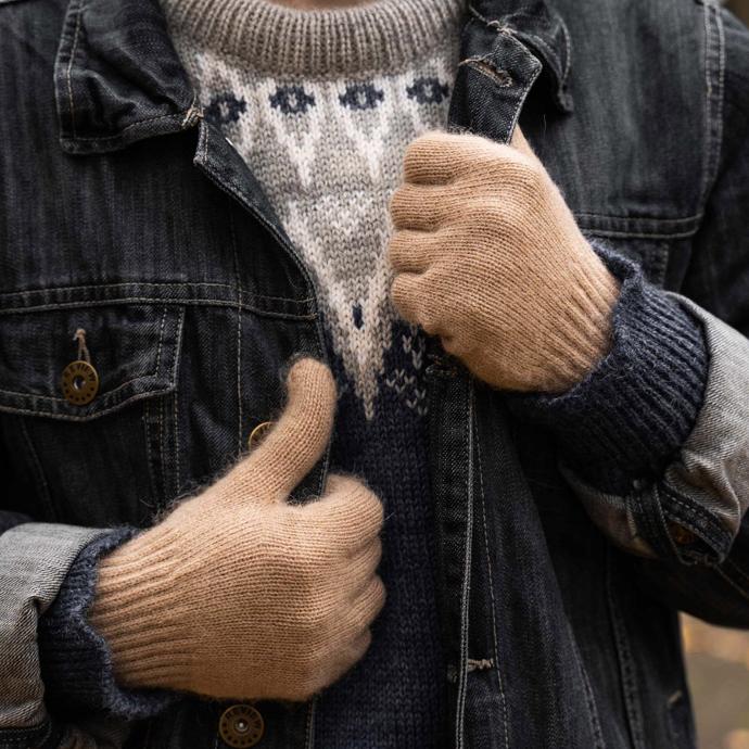 Beige woollen gloves hold a dark denim jacket
