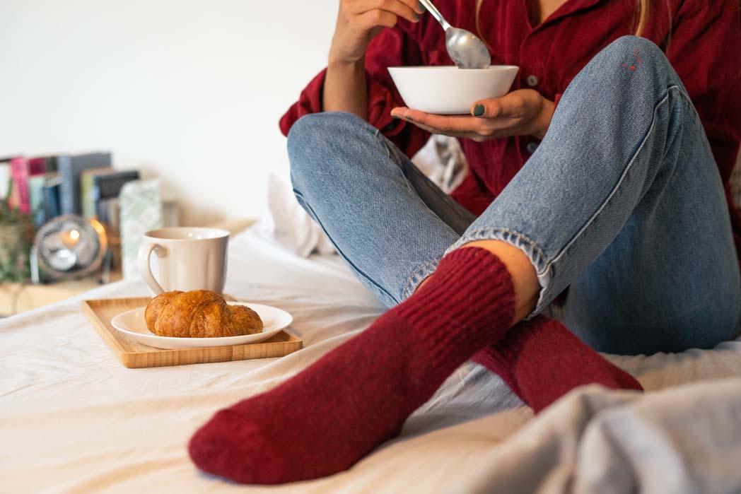 Rote Socken werden bei Frühstück im Bett getragen