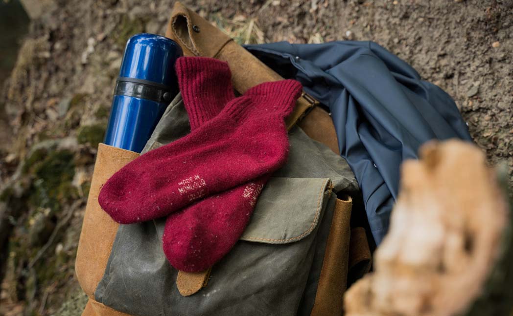 red woollen socks lying on a rucksack in the forest